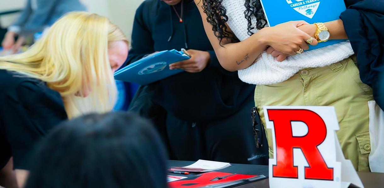 Attendees gather at a Rutgers University information table during a college transfer event.