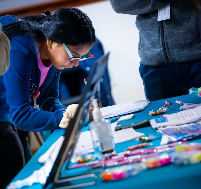 A student completes paperwork at an HCCC information table, connecting with campus resources and opportunities during a community engagement event.