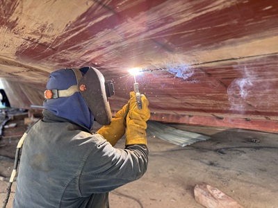 A person doing repair work on a ship.